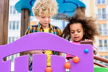 two curly multiethnic little kids having fun at playground