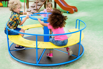 happy adorable little children riding on carousel at playground © LIGHTFIELD STUDIOS