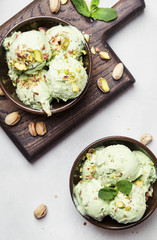 Green pistachio ice cream with mint leaves in brown bowls, top view