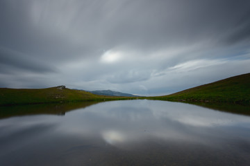 Mountain lake. Dramatic dark clouds. Water surface