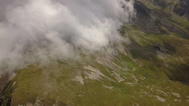 Aerial view. Panning to right over mountain landsacpe. Low altittude clouds