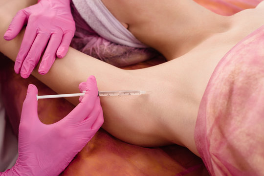 Doctor making intramuscular injections in armpit against hyperhidrosis