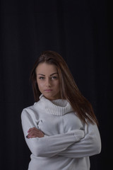 Naklejka premium Studio portrait of beautiful brunette woman wearing white sweater posing on black background