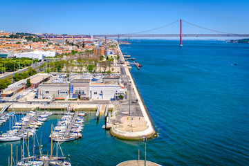 View of Lisbon from Belém. Red bridge Ponte 25 de Abril. Harbor, river and buildings.