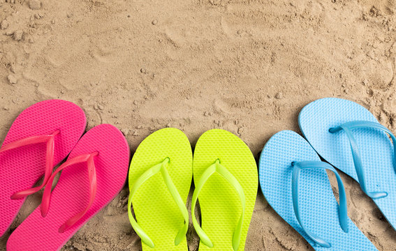 colorful flip flops in sand