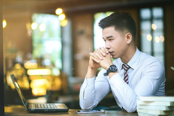 Young businessman sitting at a coffee shop.  Young business man reading a book.