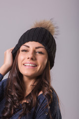 Beautiful young woman wearing sweater and woolen hat posing indoors