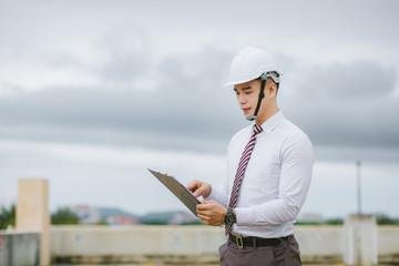  A handsome young engineer stands tall and holds a document.