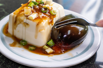 Taiwan's distinctive famous snacks: thousand-year-old eggs tofu(pidan tofu) in a white plate on stone table, Taiwan Delicacies, Taiwan Street Food