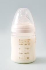 Baby bottle and milk on gray background

