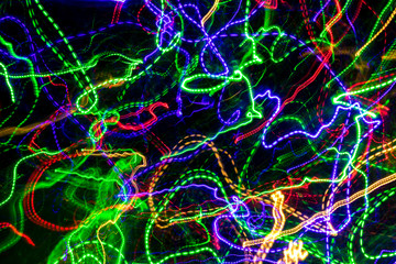 The chaotic blurred lines of color lights on dark background. Colorful lights blurred by motion.