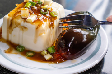 Taiwan's distinctive famous snacks: thousand-year-old eggs tofu(pidan tofu) in a white plate on stone table, Taiwan Delicacies, Taiwan Street Food