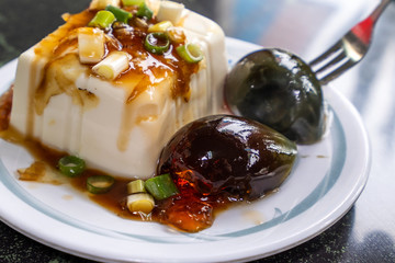 Taiwan's distinctive famous snacks: thousand-year-old eggs tofu(pidan tofu) in a white plate on stone table, Taiwan Delicacies, Taiwan Street Food
