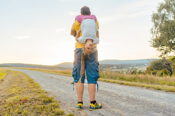 Vater trägt seine Tochter auf dem Rücken im Sommer in ländlicher Landschaft