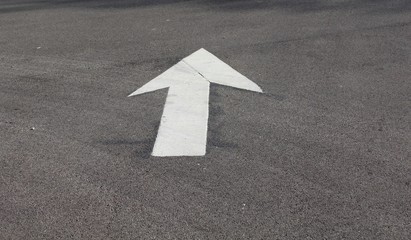 The painted white arrow point up on the blacktop road.