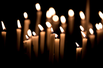 Many burning candles - Light of candels in the church on the black background