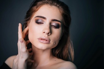 Fototapeta premium beauty portrait. Studio portrait of a beautiful girl on a gray background. Good make-up. Face close-up