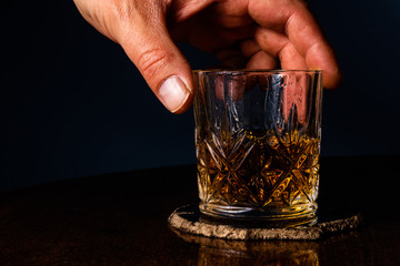 A hand putting back a crystal tumbler filled with whiskey