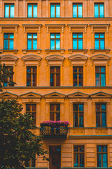 Fototapeta premium orange and historical facade of apartment building in high format with an small balcony and pink flowers