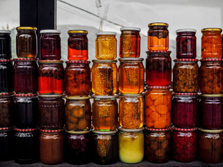stacks of jars with honey and pickled fruits on market at armenia