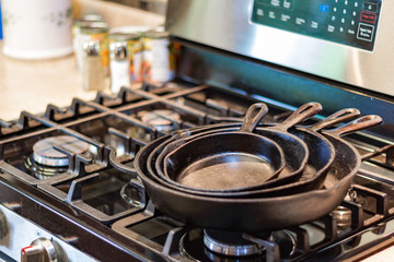 Iron skillets stacked on top of a stove top in a kitchen.