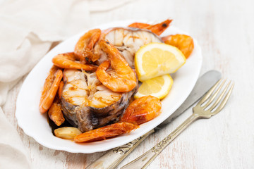 boiled fish with shrimps and lemon on white dish