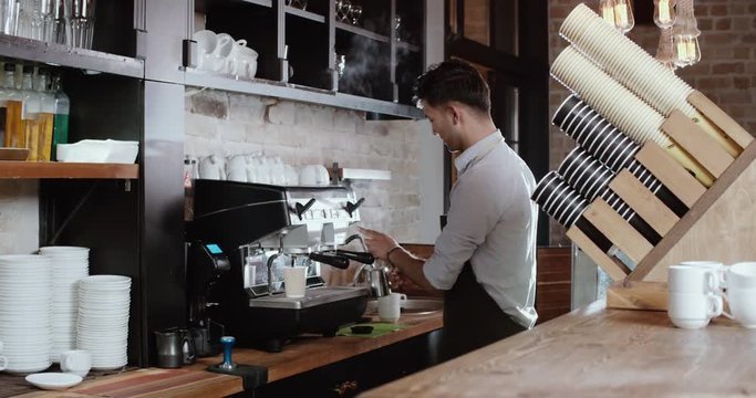 young handsome asian barista serving a customer in coffee shop, brewing coffee, then looking at camera, talking and smiling - small business, people and serving, lifestyle concept 4k