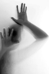 Silhouette of hand behind glass foreground
