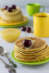 Pancakes for breakfast on multi-colored plates and fresh berries on a sunny morning