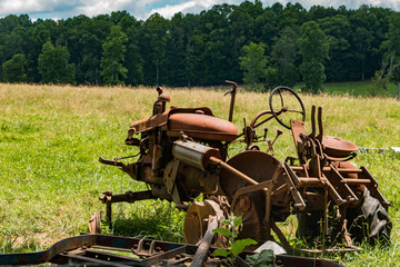 A red, rusty old tractor in a feild of green grass.