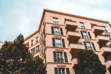 Fototapeta premium orange apartment building with green trees and cloudy sky