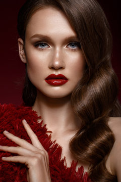 A beautiful girl with evening make-up, a Hollywood wave and red lips. Beauty face. Photo taken in the studio.