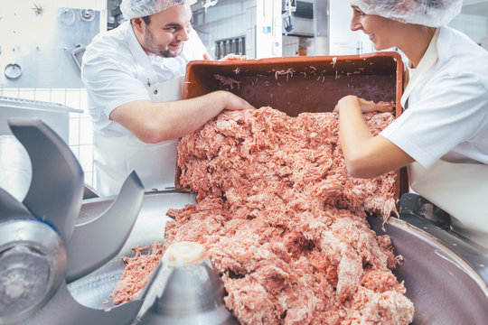 Team von Fleischern nimmt Hackfleisch aus dem Kutter zur weiteren Verarbeitung