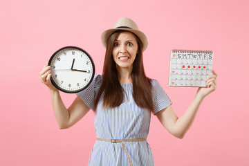 Shocked confused sad woman in blue dress holding round clock, periods calendar for checking...