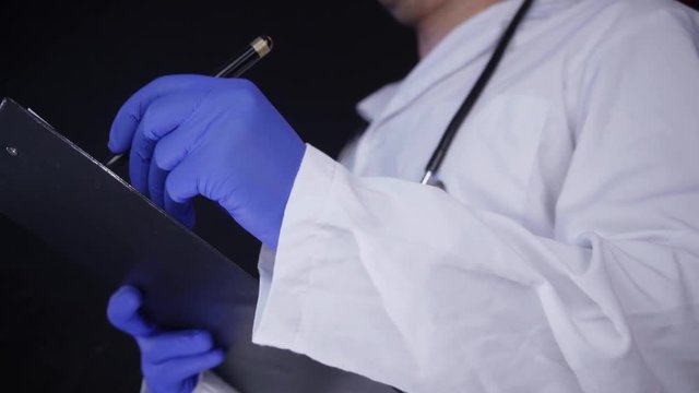 Doctor writing on a notepad information. Taking notes closeup shot. Shot isolated on black background.