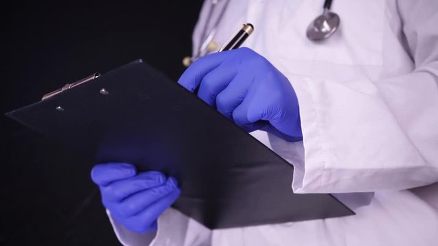 Close Up Caucasian male Doctor hand writing rx prescription. Shot isolated on black background.