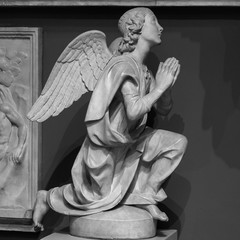 Statue of a white stone angel praying in a cemetery