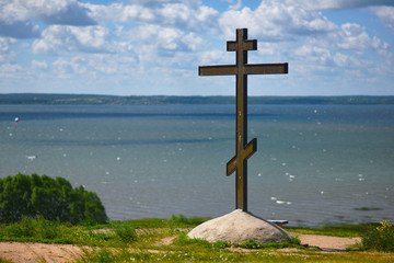 Orthodox cross on a hill on the lake