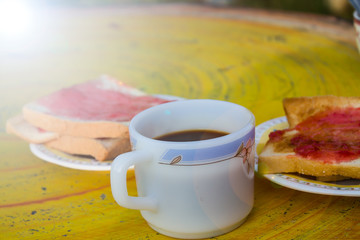 White Coffee Cup Place it on a yellow table with baking bread. Make red strawberry jam