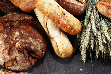 Different kinds of bread and bread rolls on board from above. Kitchen or bakery