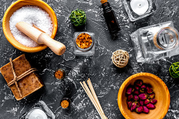 spa cosmetics with soap, salt, oil on dark background top view