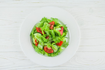 light summer salad with vegetables, on a wooden background