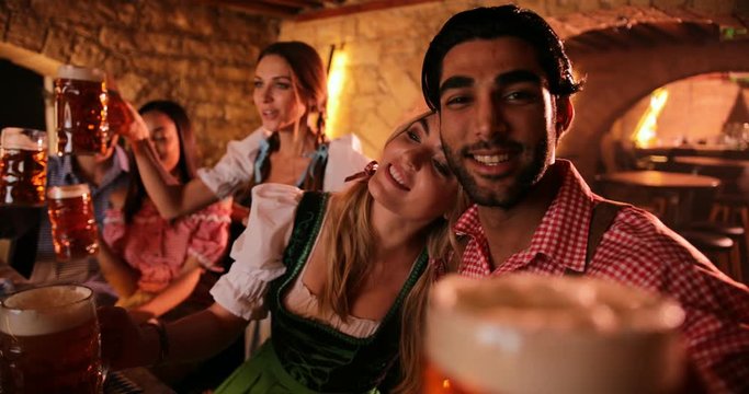 Young multi-ethnic friends celebrating Oktoberfest with beer in traditional bar