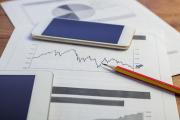 Investment charts with laptop and calculator on wooden table workplace
