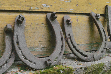 Background surface of very old and rusty horseshoes placed near the wall