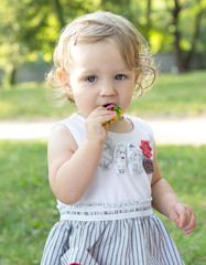 Little girl eat candy in the open air in summer