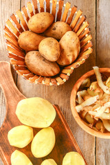 Men's hands clean potatoes for okroshki on an old wooden table.