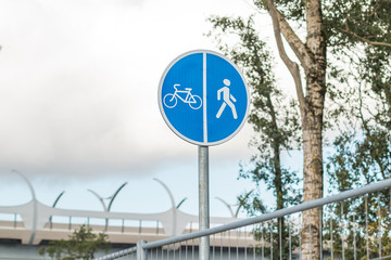 Sign for pedestrians and cyclists near a road in the park. Close up shot.Bicycle and Walking Path Sign with Sky Background.Copy space. Sport outside.Bicycle and pedestrian blue sign, board
