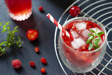 Red berries cocktail close up on the dark backdround