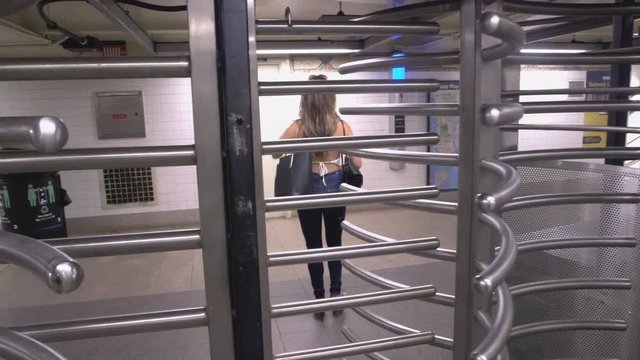 Young Caucasian Woman With Long Brunette Hair Walks Into The New York City Subway System Through A Turnstile
